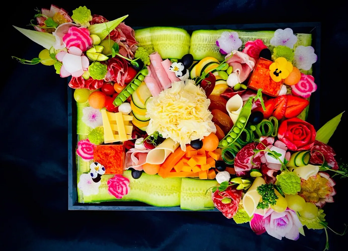 Plateau garni de charcuteries, fromages et légumes sculptés en roses.