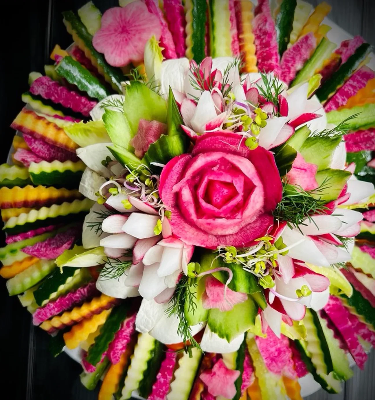 Rosace de radis pastèque, concombre et carotte rayonnant autour d’une rose sculptée.